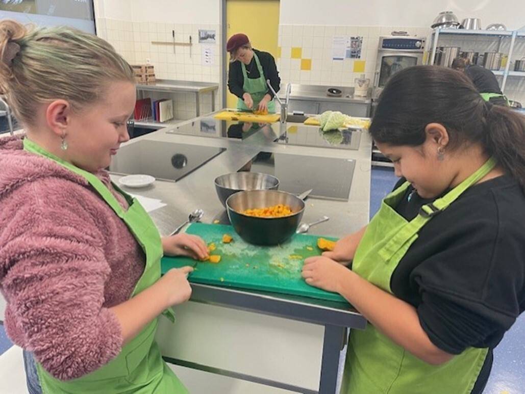 twee kinderen snijden groente in een keuken