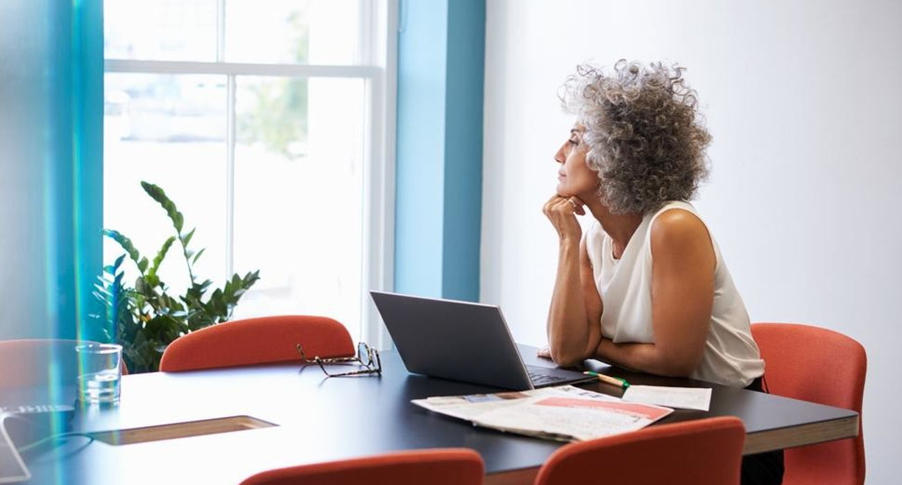 Nadenkende vrouw achter laptop